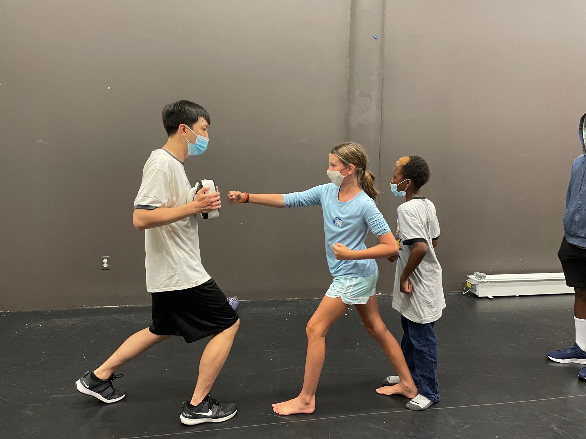 A young girl and boy practicing martial arts with a teacher...