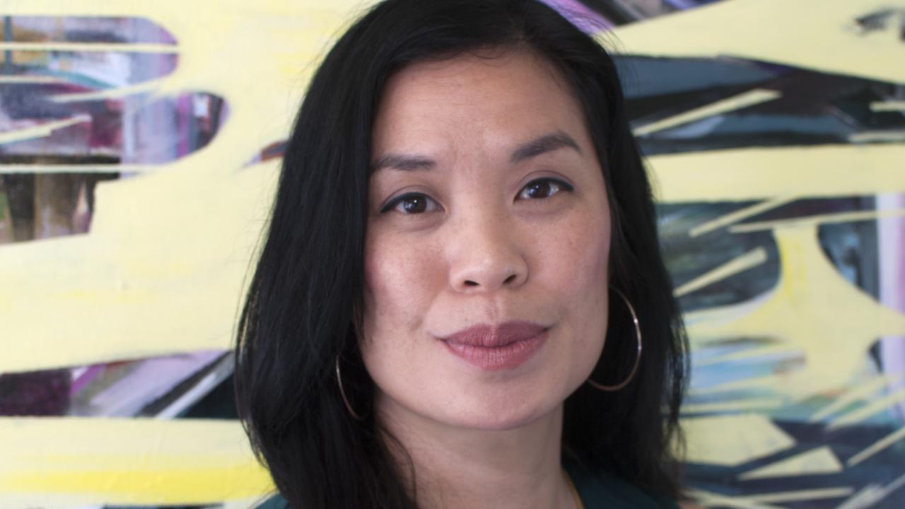 Headshot of Sisavanh Phouthavong in front of a colorful background.