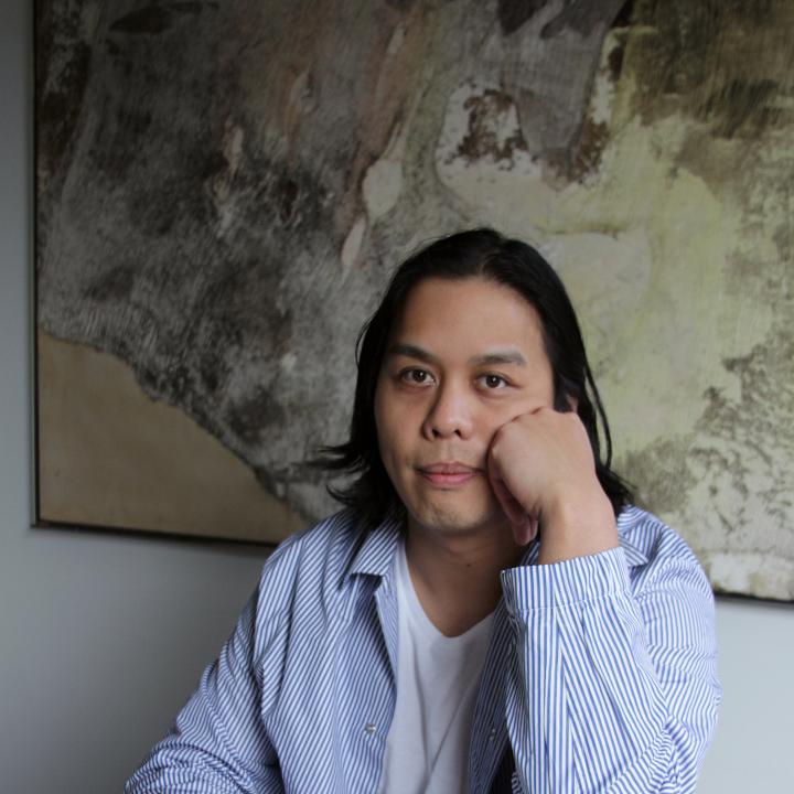 Headshot of Alex Nguyen-Vo in front of a painting.