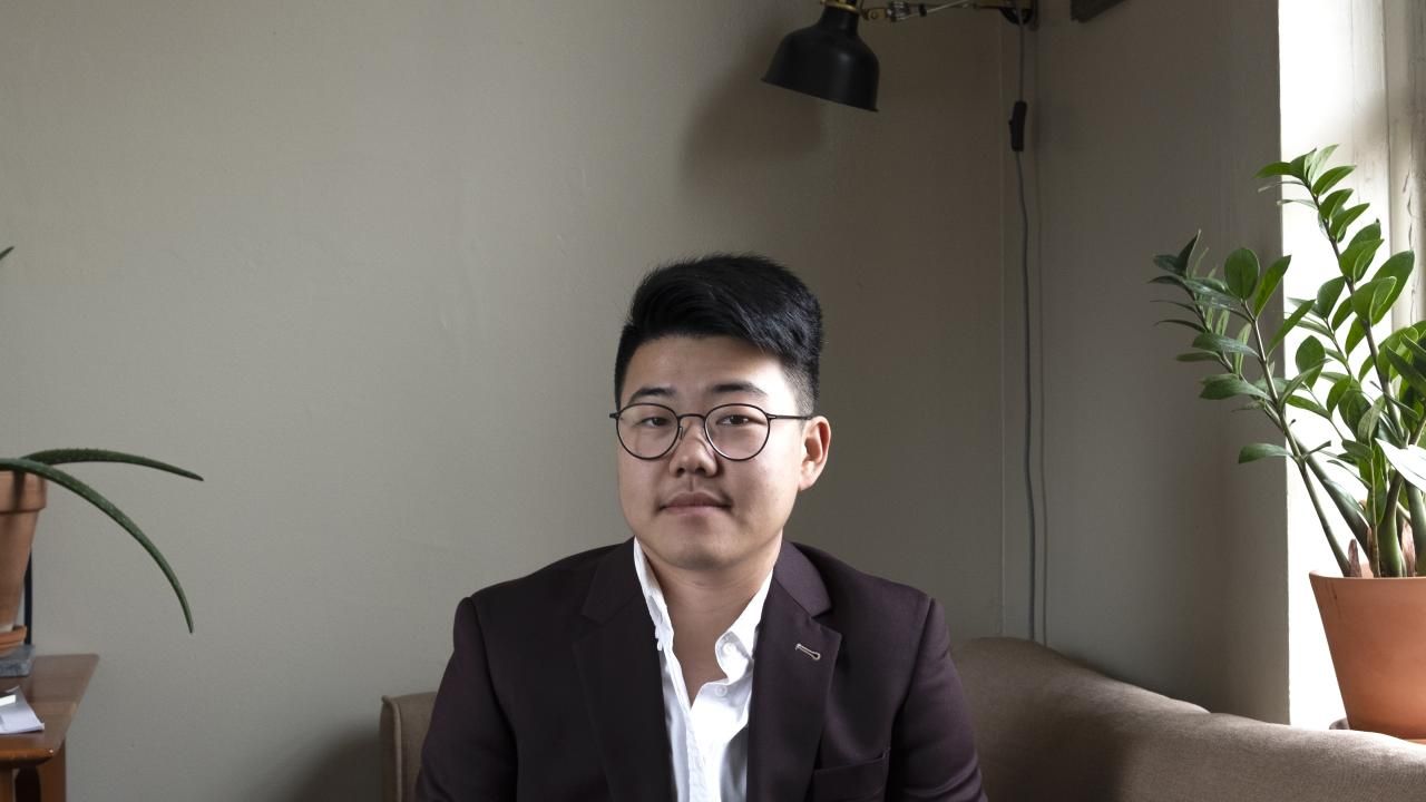 Headshot of Yanyi in a minimalistic office space.