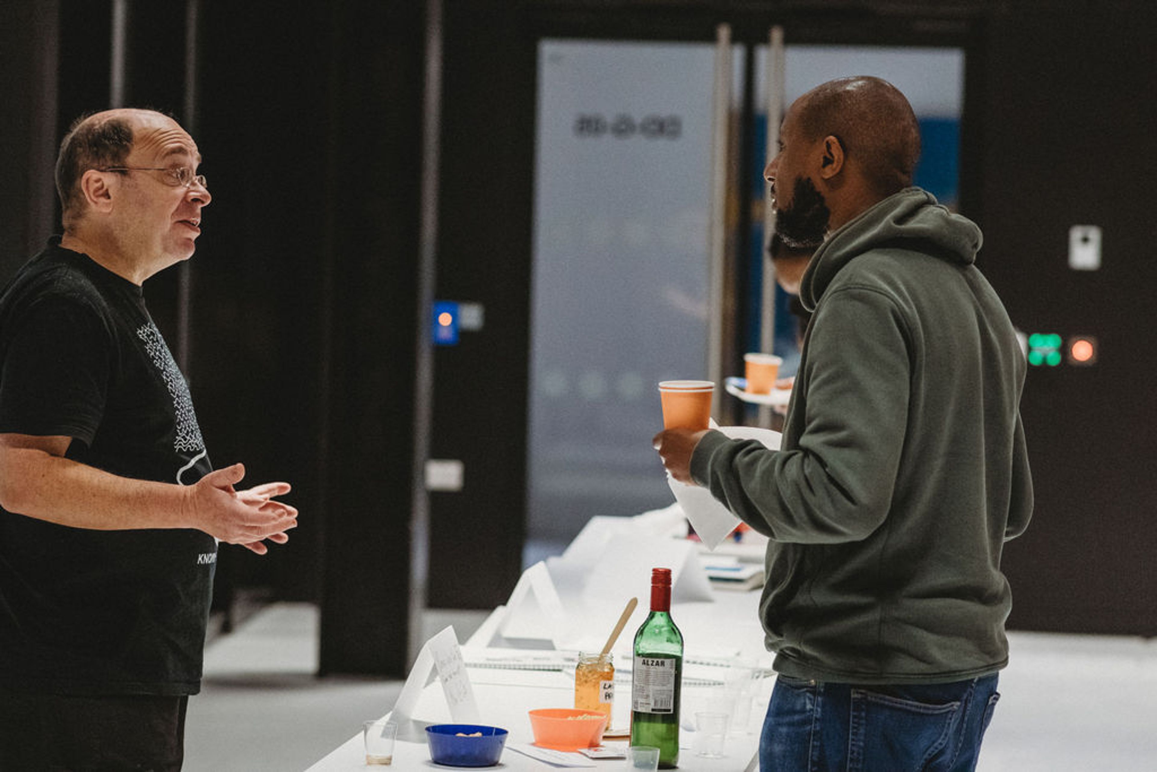 Two men converse during an event across a table.