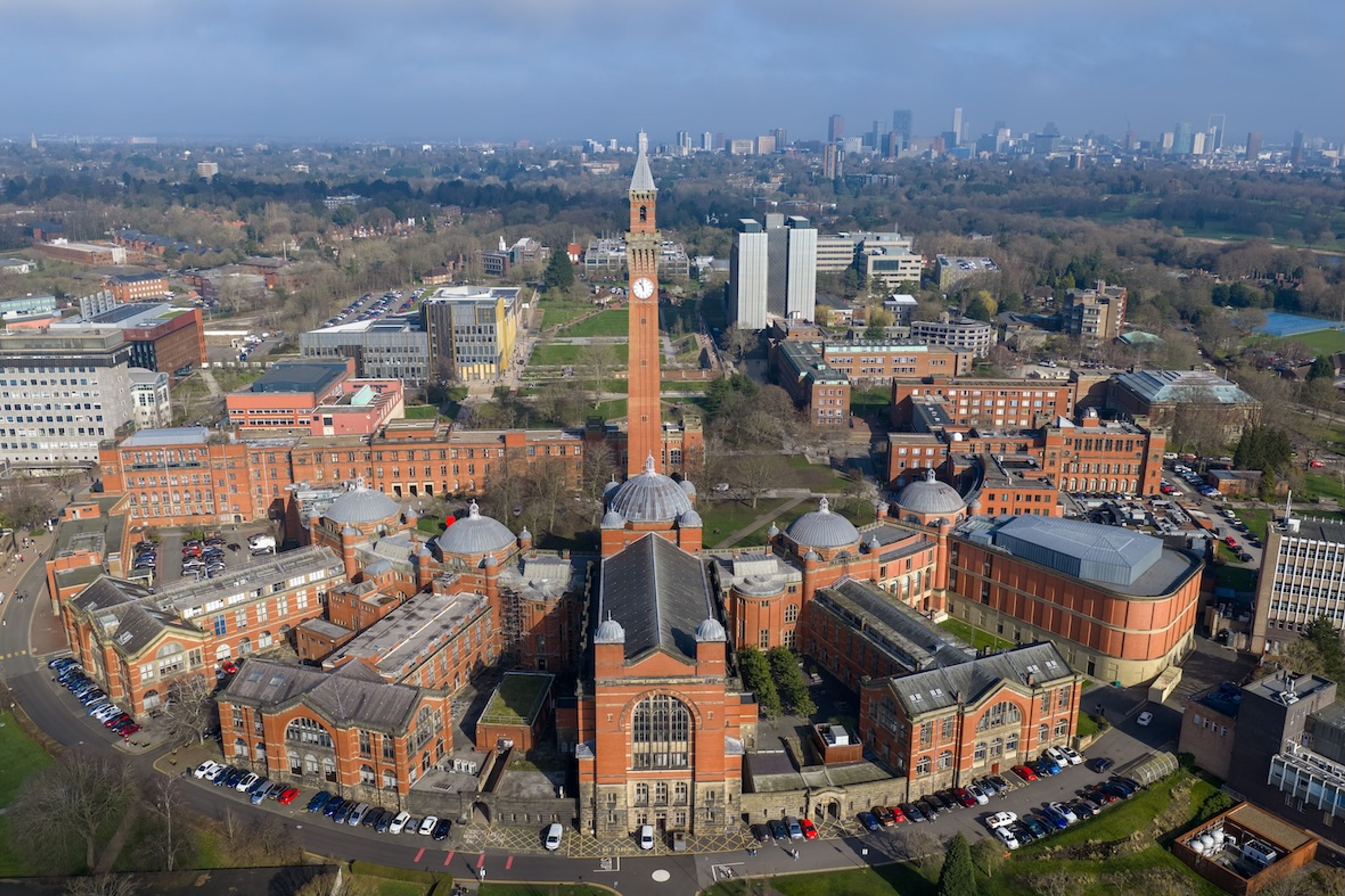 A Birds Eye view of the University of Birmingham which includes red brick buildings in a circular formation around a tall clock tower