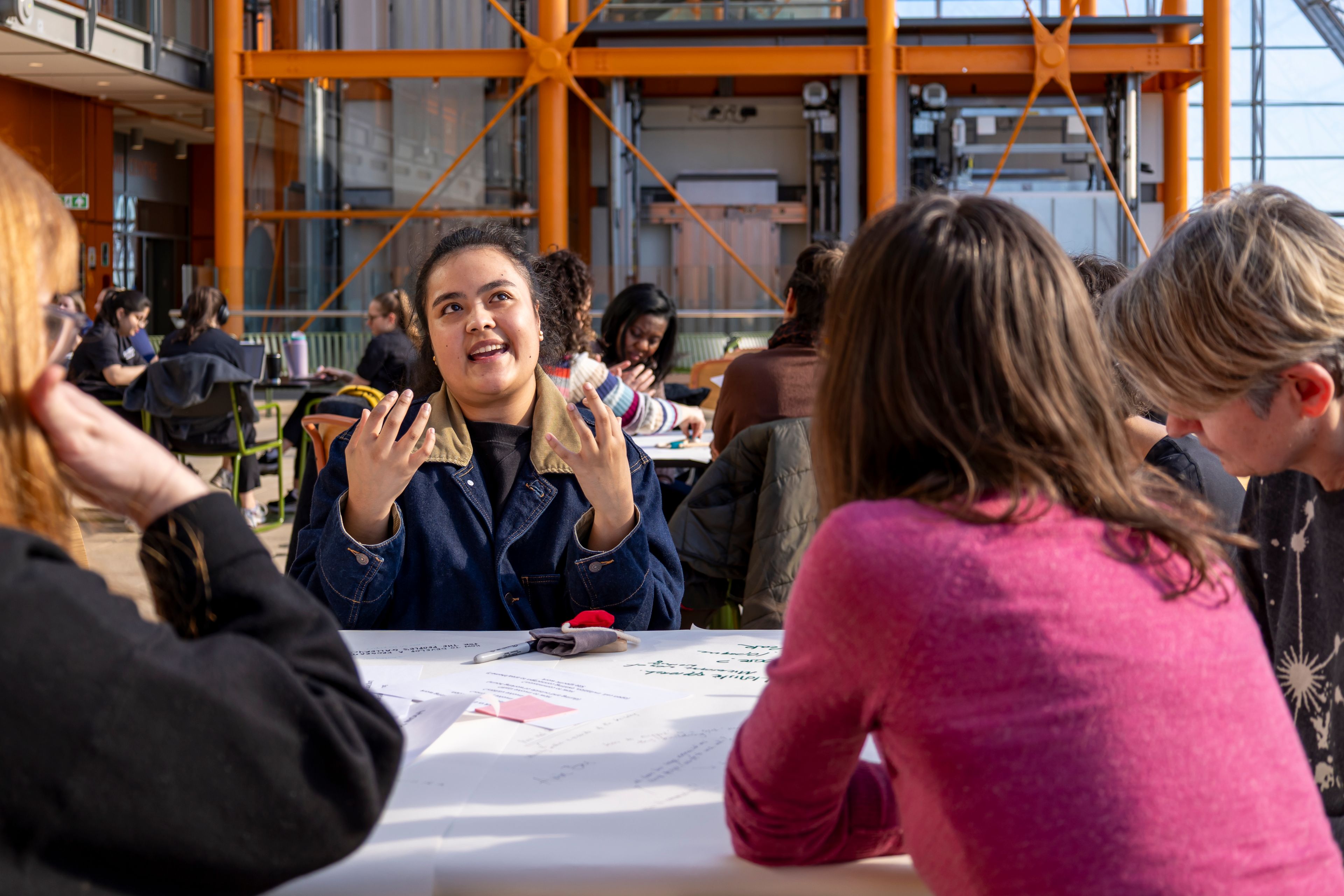 A group of people are sat around a table, they are animated and deep in conversation.