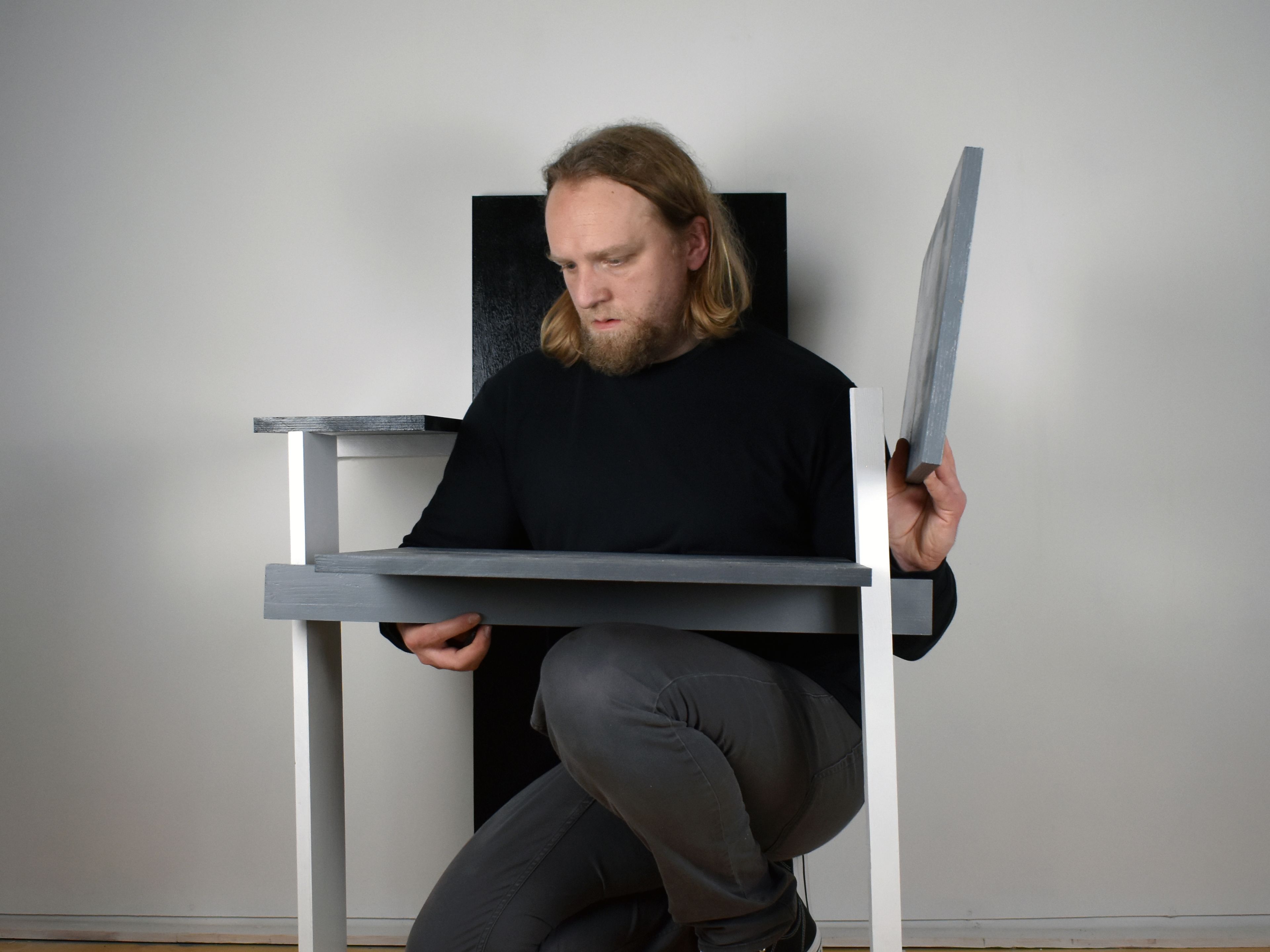 Daniel in the centre of a flatpack chair, kneeling.