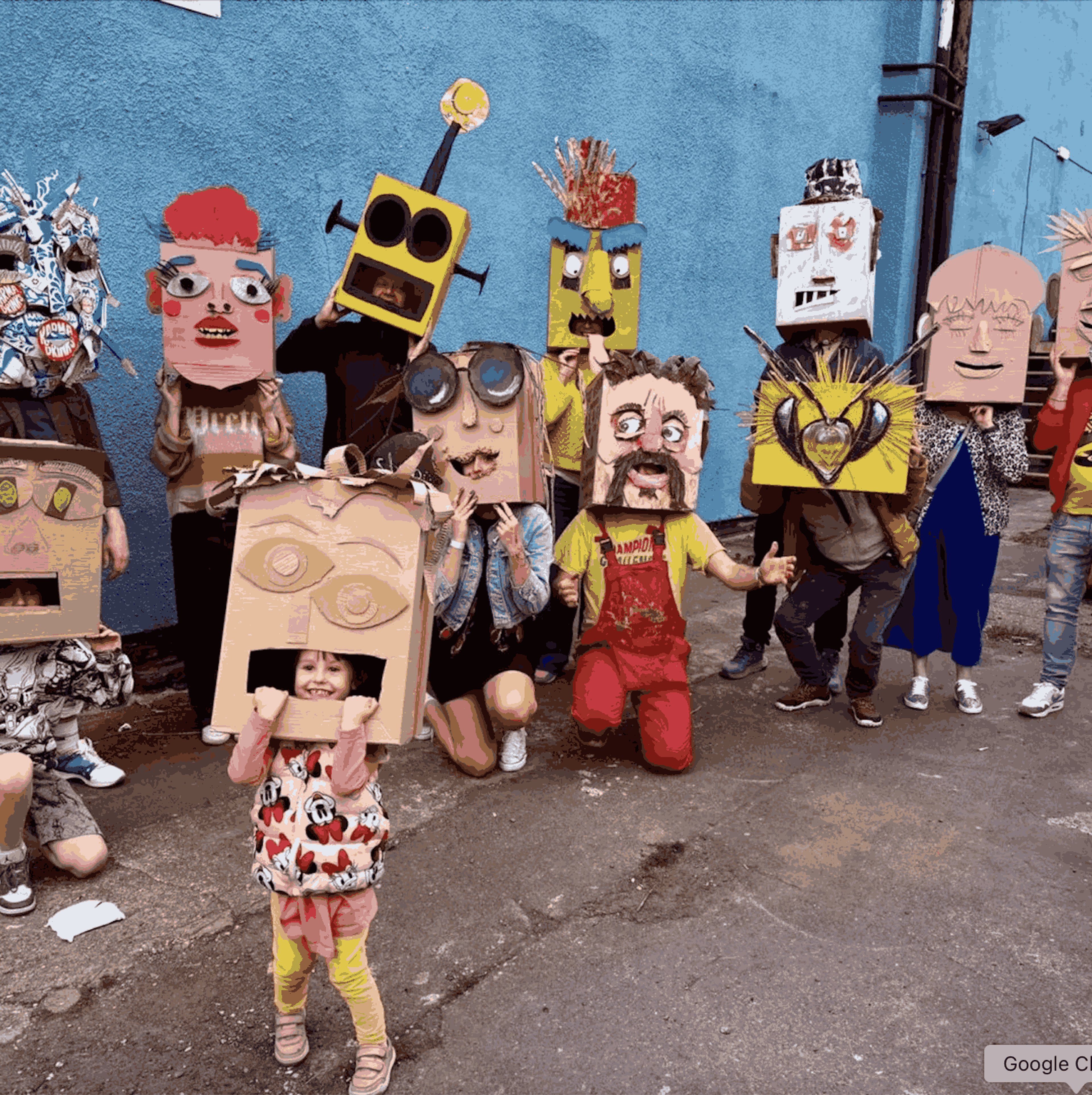 A small group of people posing for the camera, faces obscured by hand-painted, cardboard masks.