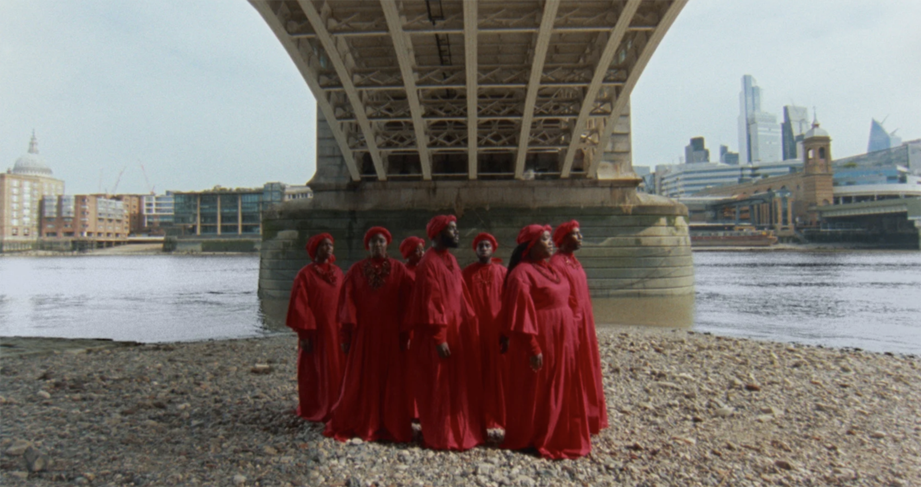 A group of people dressed in red under a bridge.
