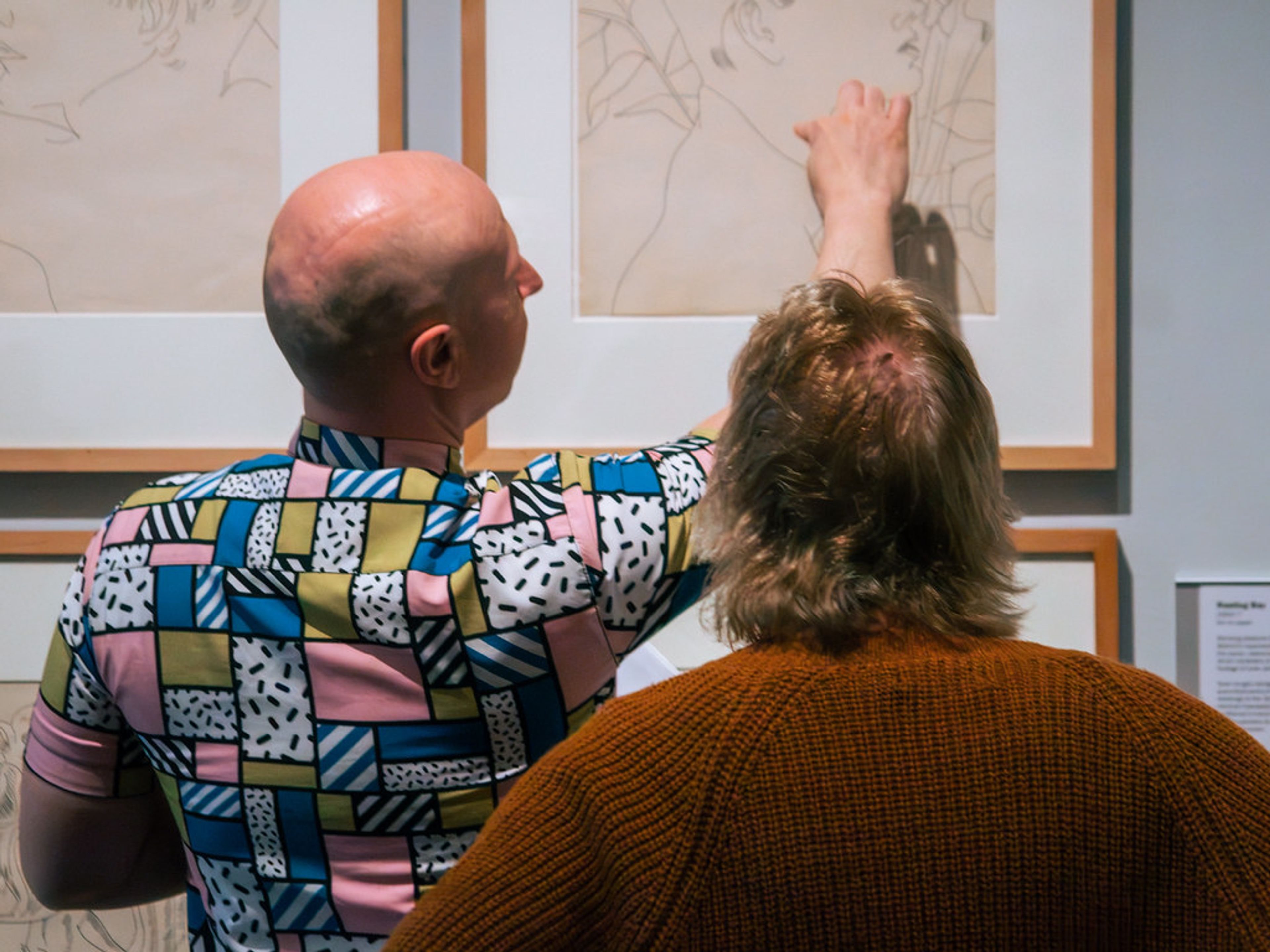 Photograph of Jon Sleigh and a gallery attendee looking at works in the Andy Warhol: Art Star exhibition