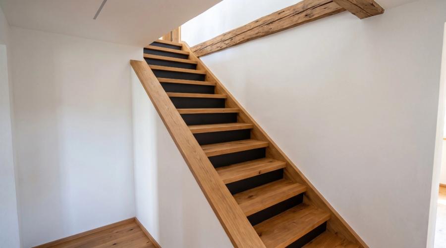 Fertige Treppe aus Eiche mit schwarzen Setzstufen und Altholzbalken, gebaut von der Schreinerei Gleinig