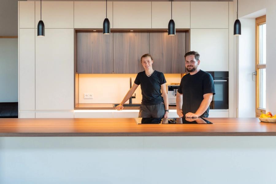 Moderne Penthouse-Küche aus Nussbaum mit Kochinsel und schwarzen Pendelleuchten