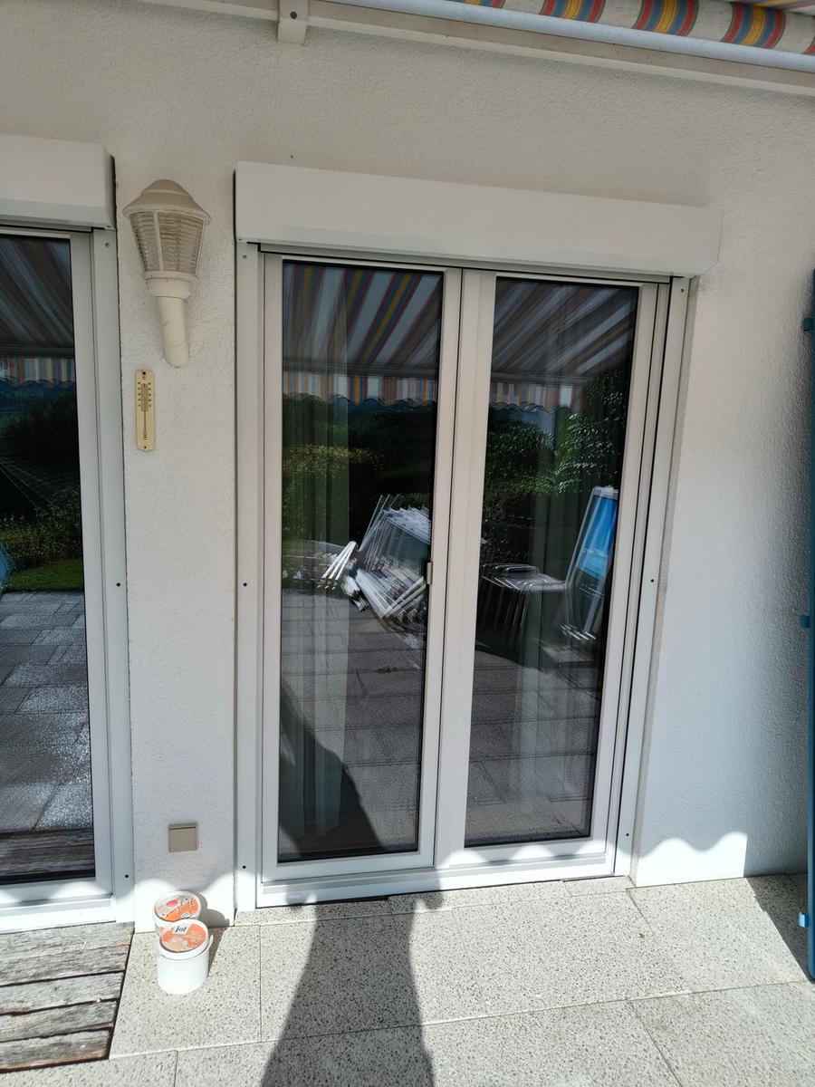 Kunststoff Terrassentür mit farbiger Markise reflektiert