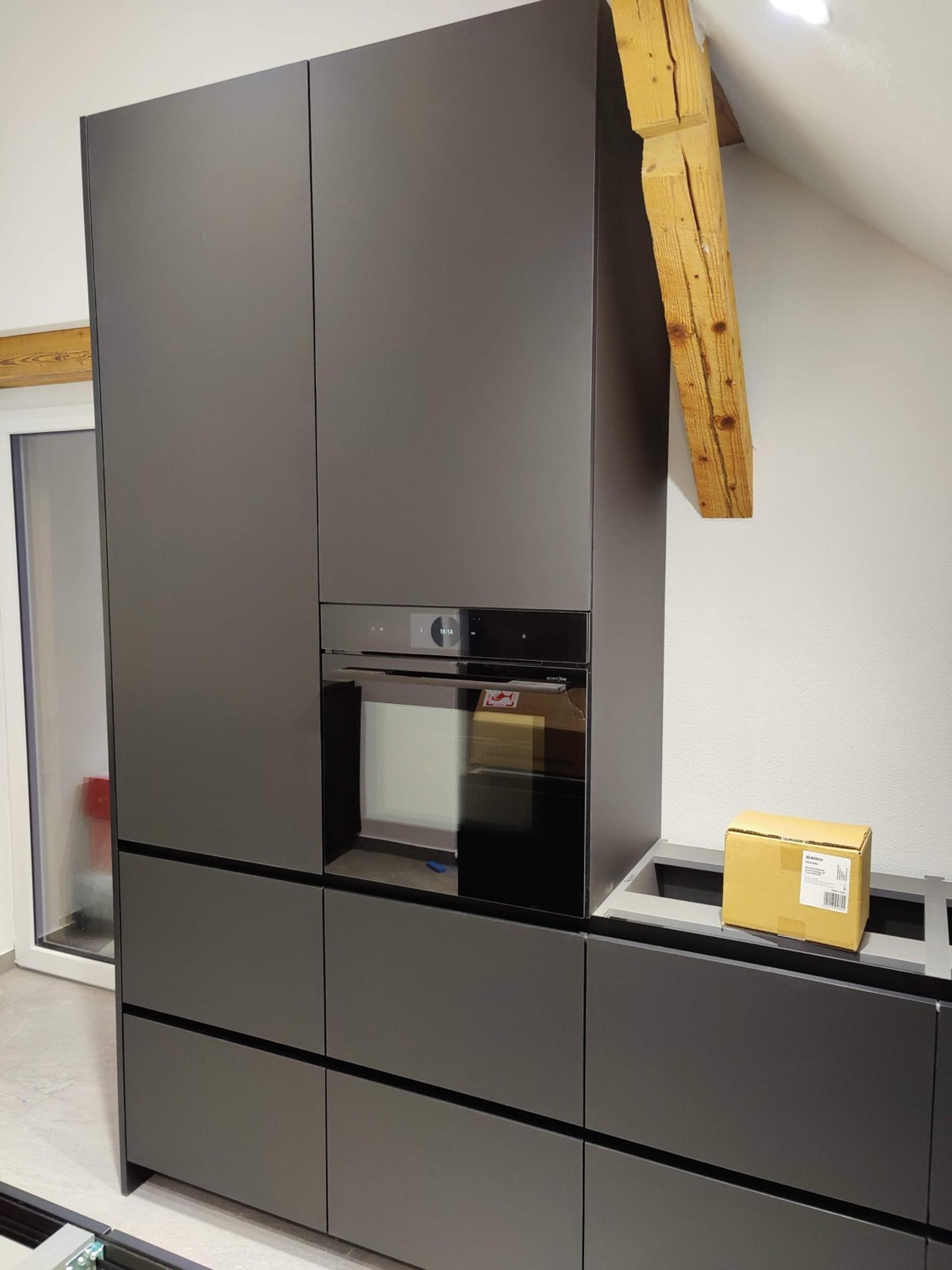 Schwarze Küchenzeile mit Holzrahmen und integriertem Backofen