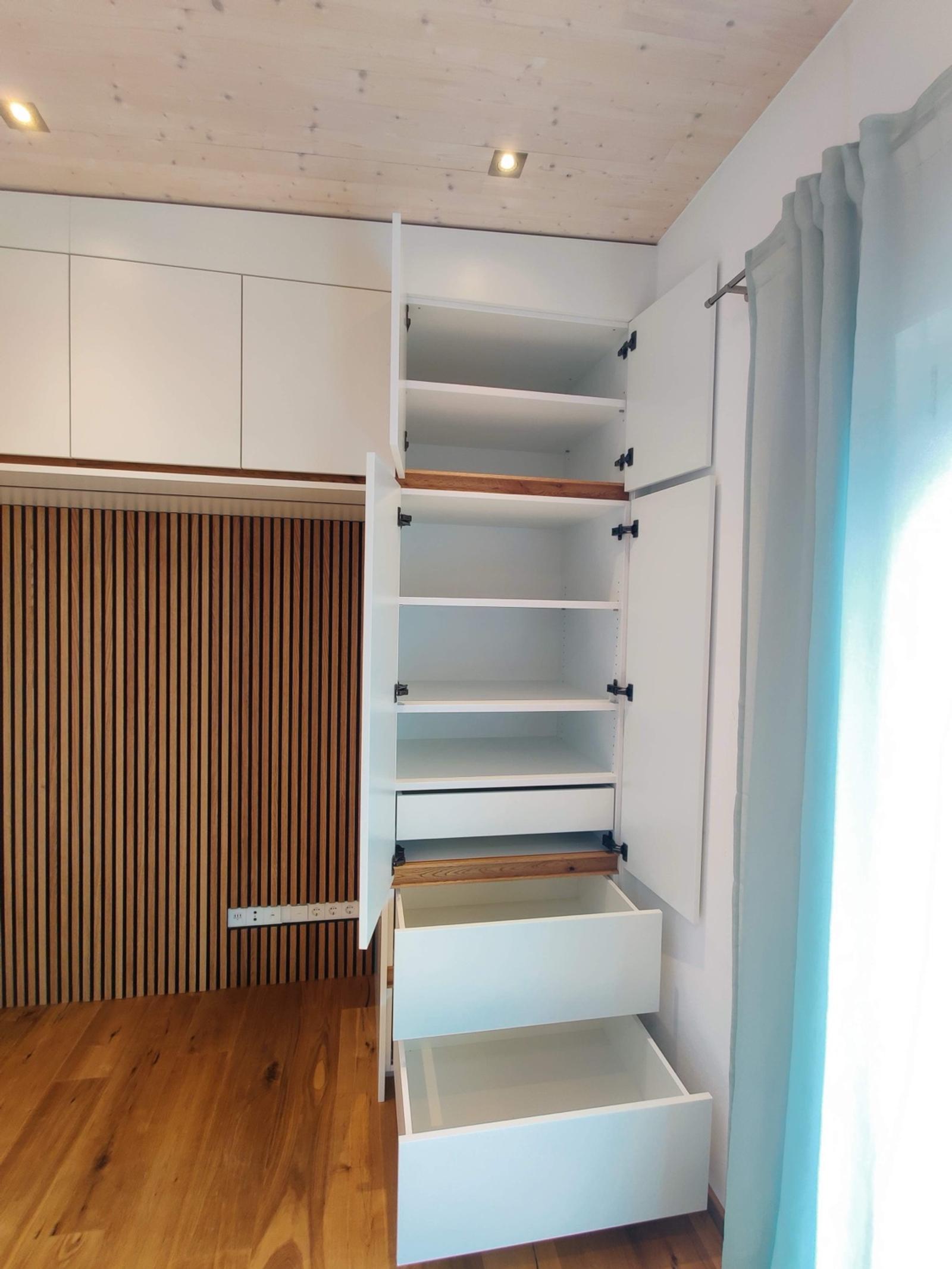 Moderne Schrankwand mit weißen Türen, Holzakzenten und offenen Schubladen