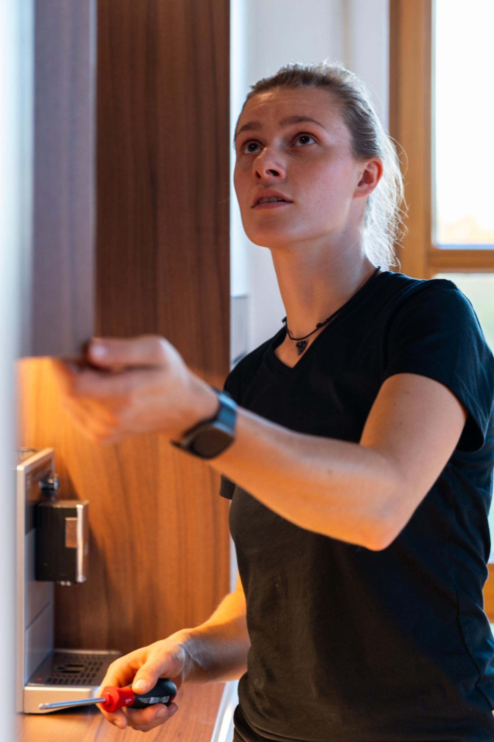 Stefanie Gleinig repariert Kaffeemaschine in Holzschrank