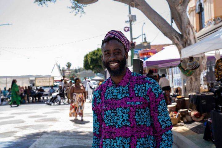 A man in a purple and teal print shirt and cap smiles on Degnan Boulevard