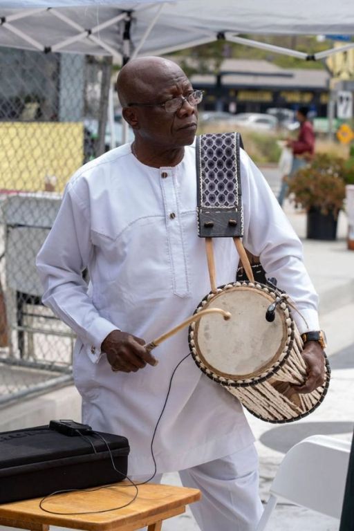 An elder in white plays the gángan talking drum
