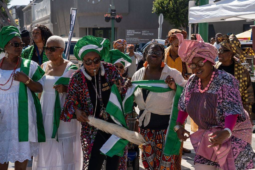 Women in white with green and white sashes dance in the procession