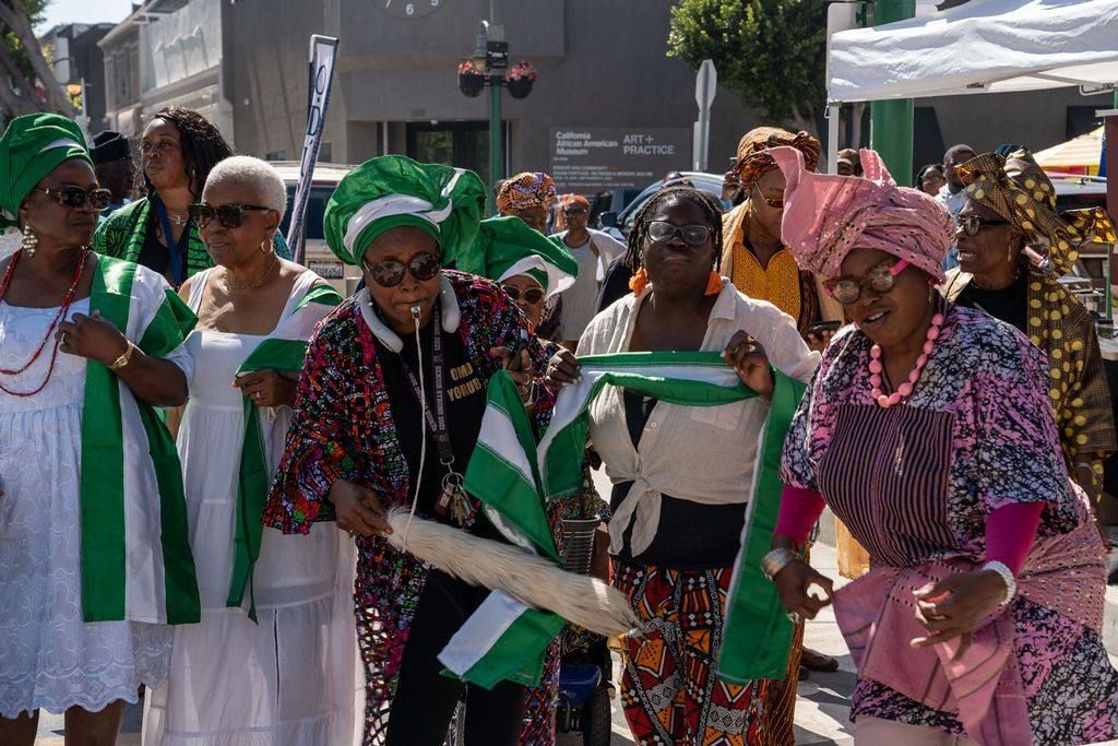 Women in white with green and white sashes dance in the procession