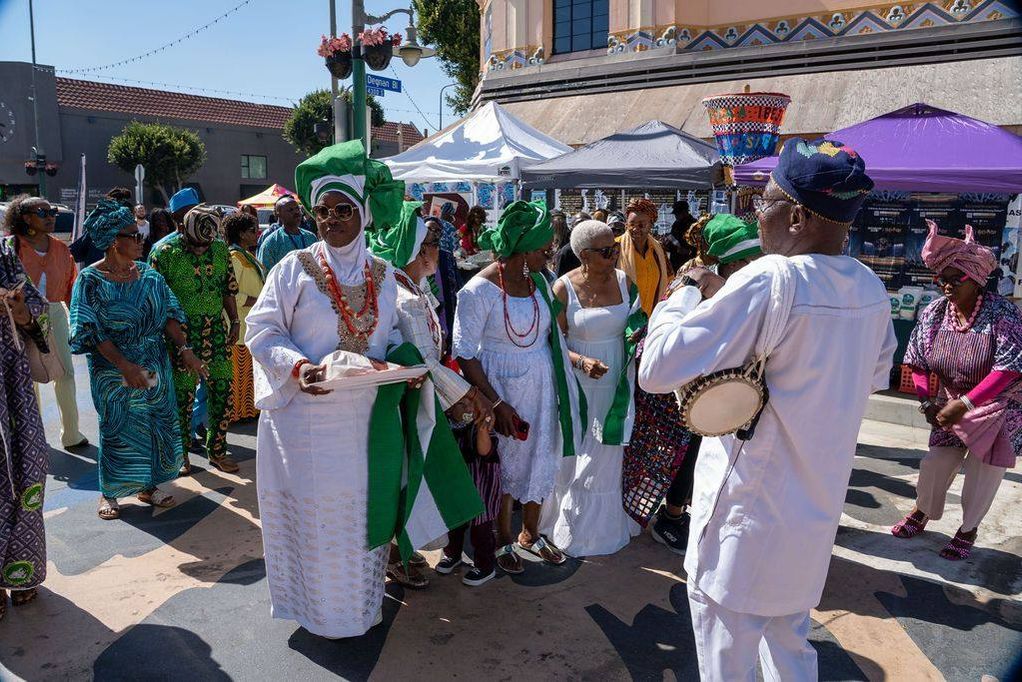 The procession moves down Degnan Boulevard led by a gángan drummer in white