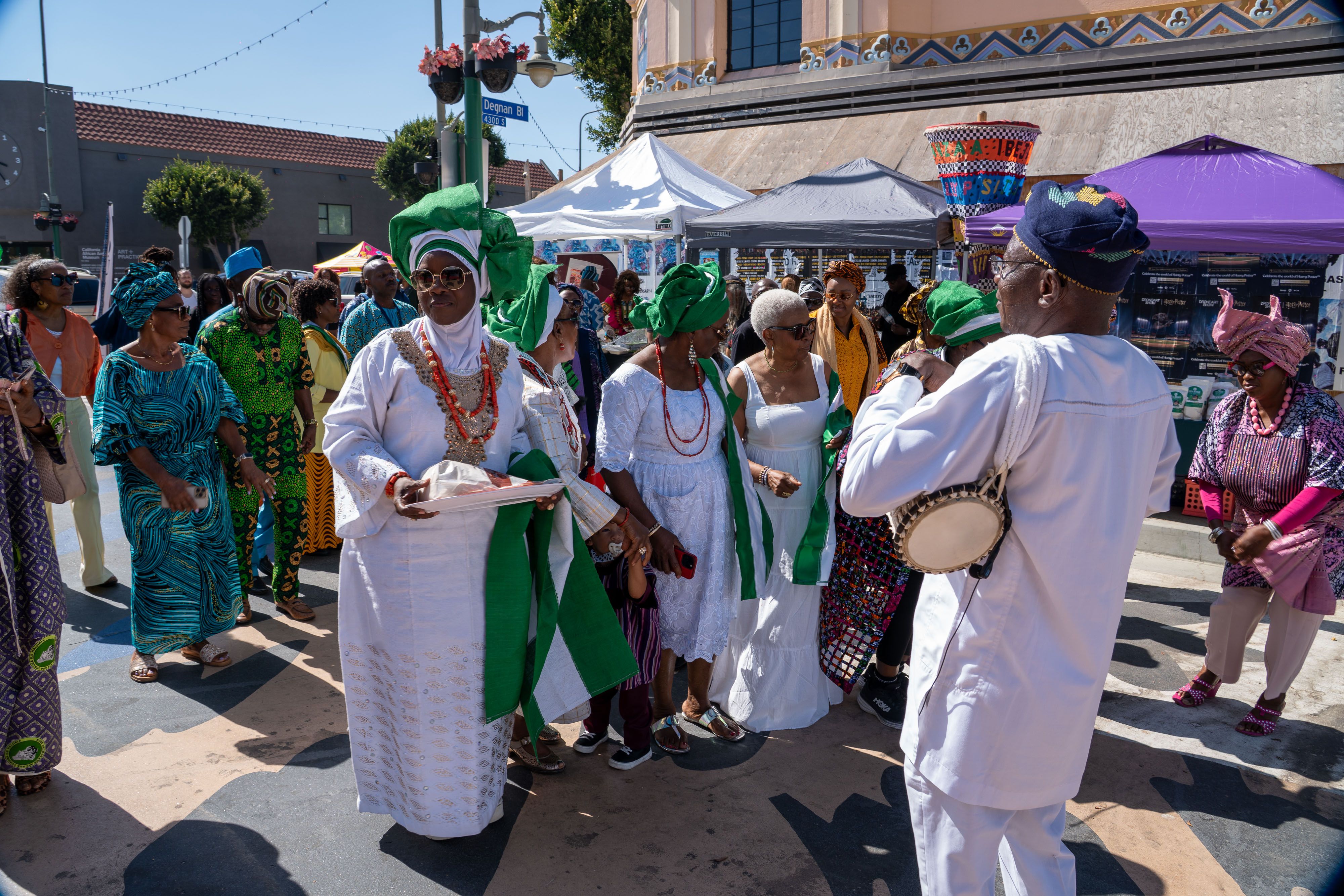 The procession moves down Degnan Boulevard led by a gángan drummer in white