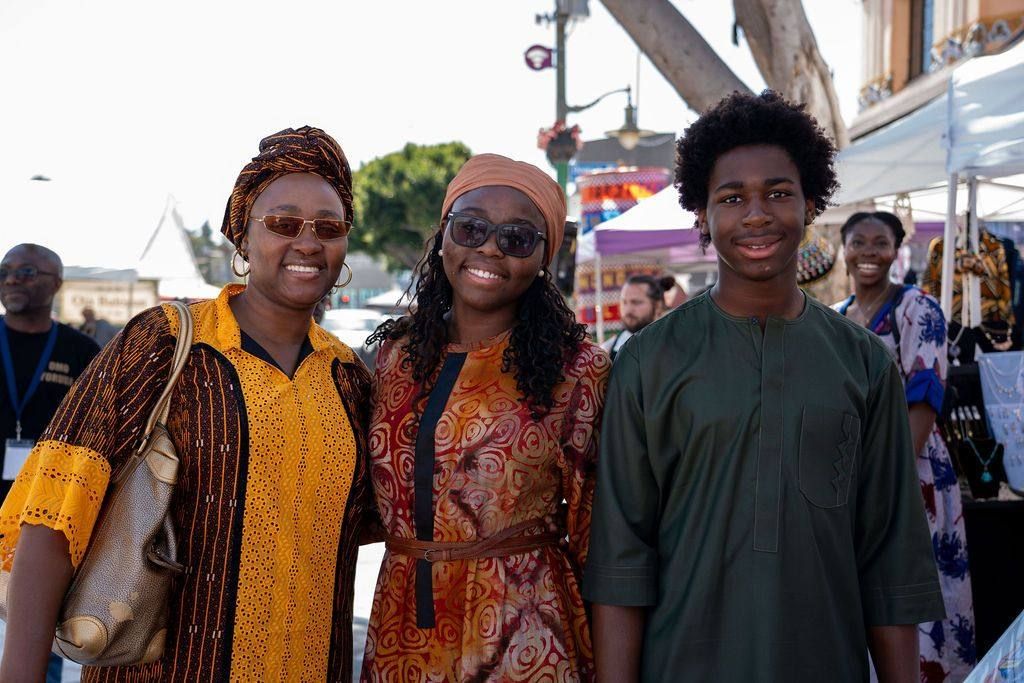 A mother, daughter and son in matching festival dress smile together