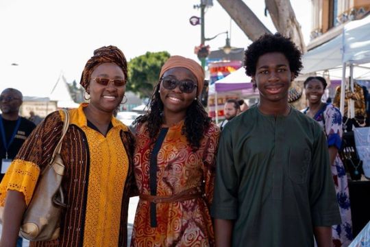 A mother, daughter and son in matching festival dress smile together