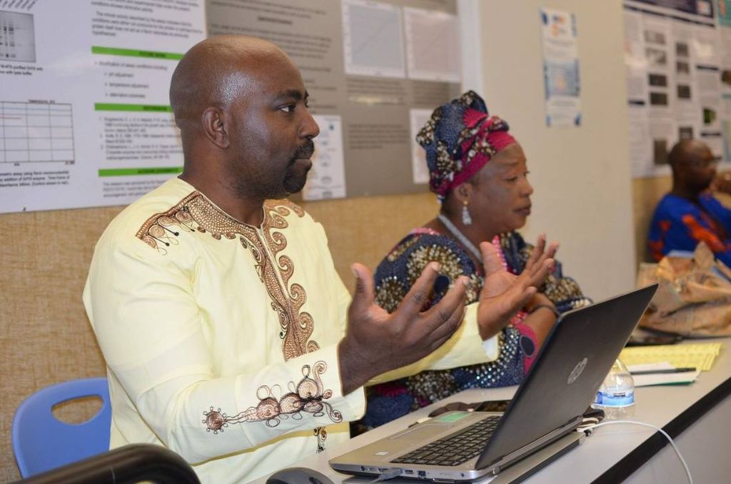 Two teachers speak from behind a laptop in the lecture room