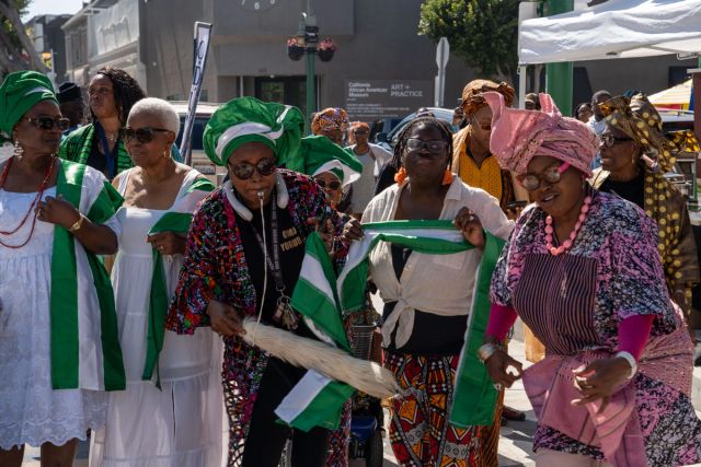 Women in white with green and white sashes dance in the procession