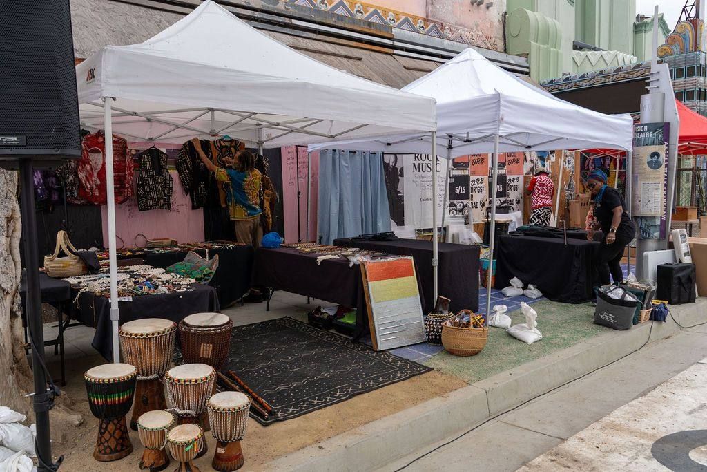 Vendor tents with drums set out on the pavement below the Vision Theatre