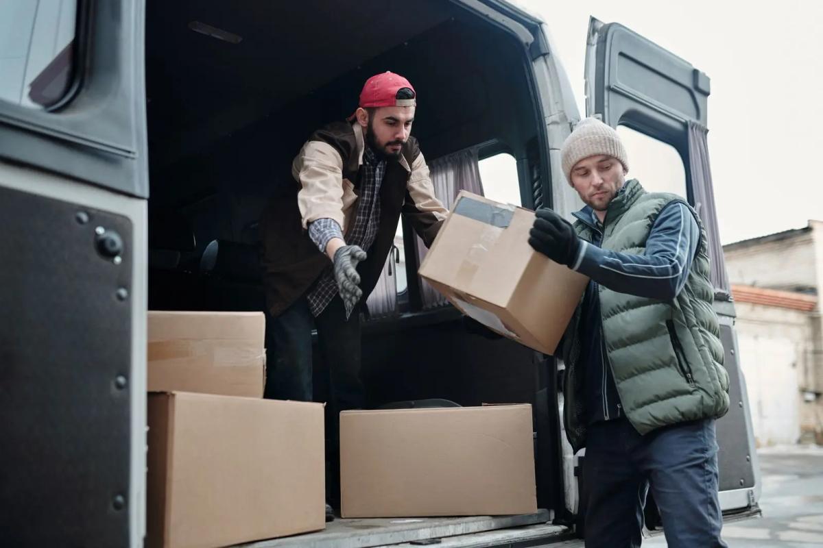 Twee koeriers laden dozen uit een bestelbus