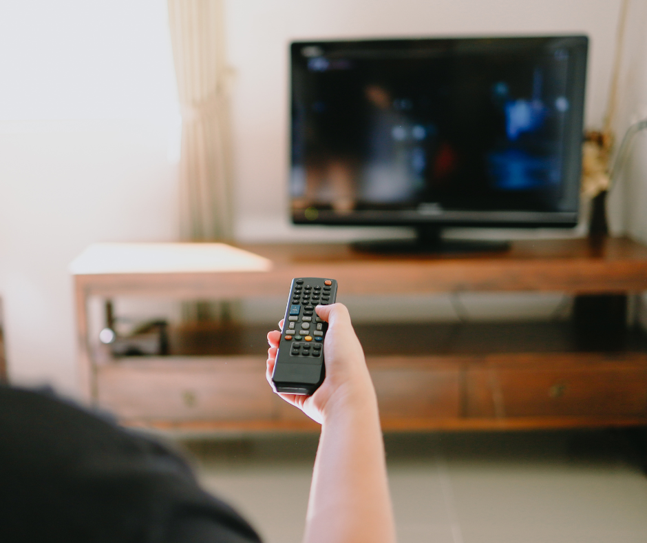Person pointing remote at TV