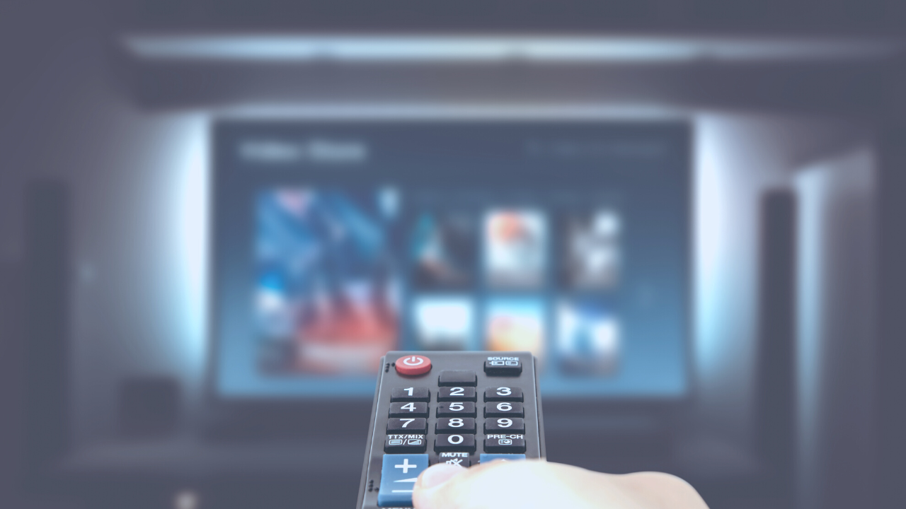 Person holding a remote in front of a tv 