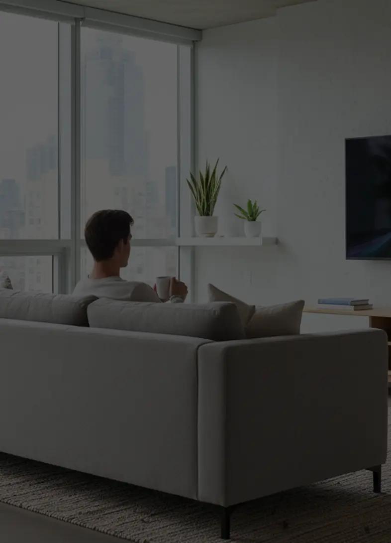 Person sitting on a couch, looking towards the television.