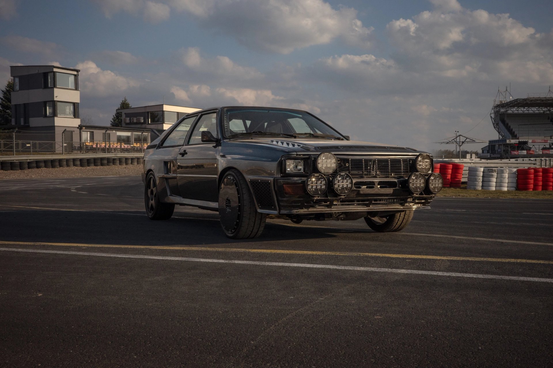 Front three-quarter view of the Audi ur-quattro on track showing the rally light bar and wide aramid body