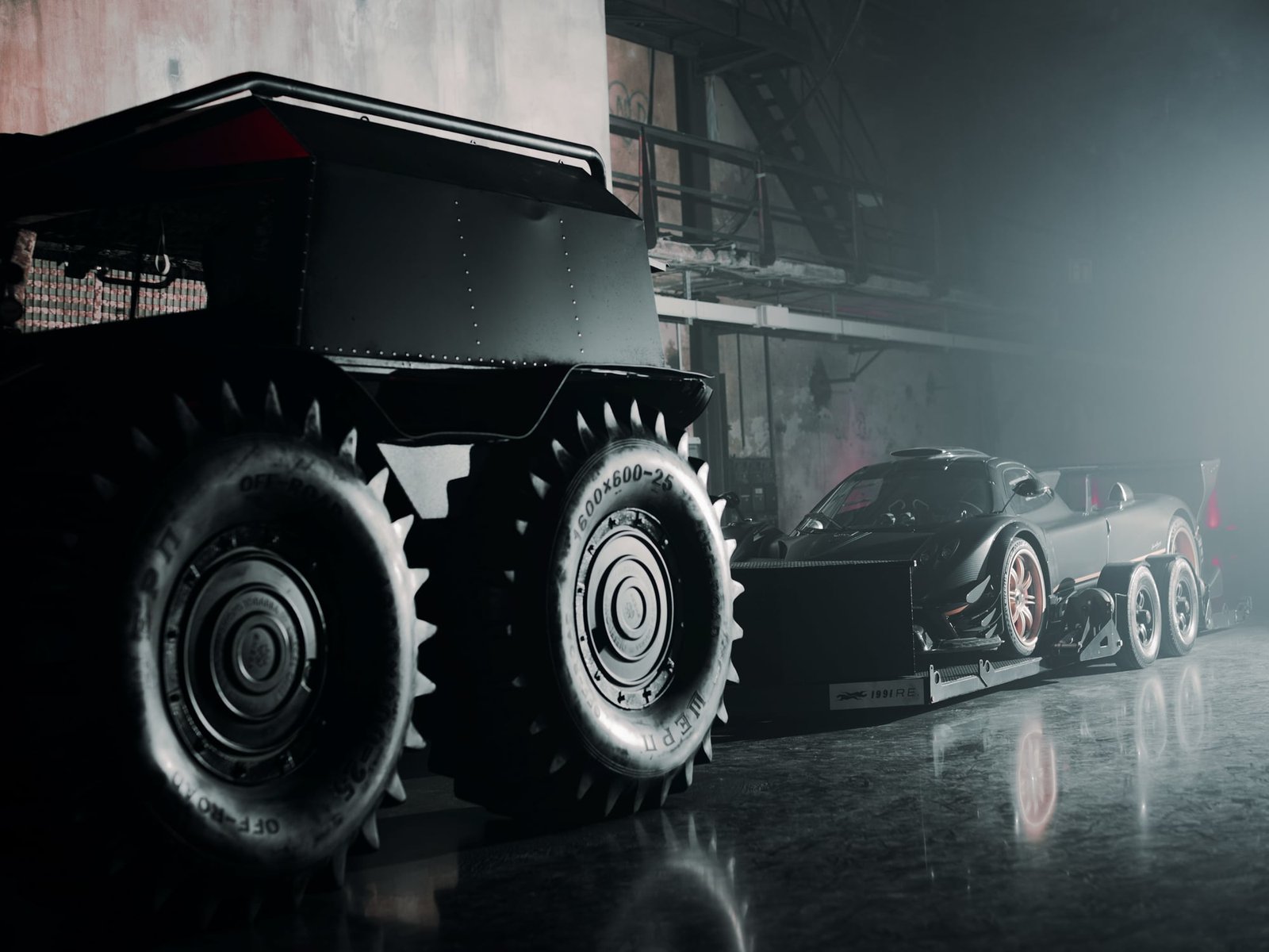 Massive black six-wheeled armored vehicle with spiked off-road tires in the foreground, a black hypercar visible behind it, in a dimly lit Areal Böhler hall