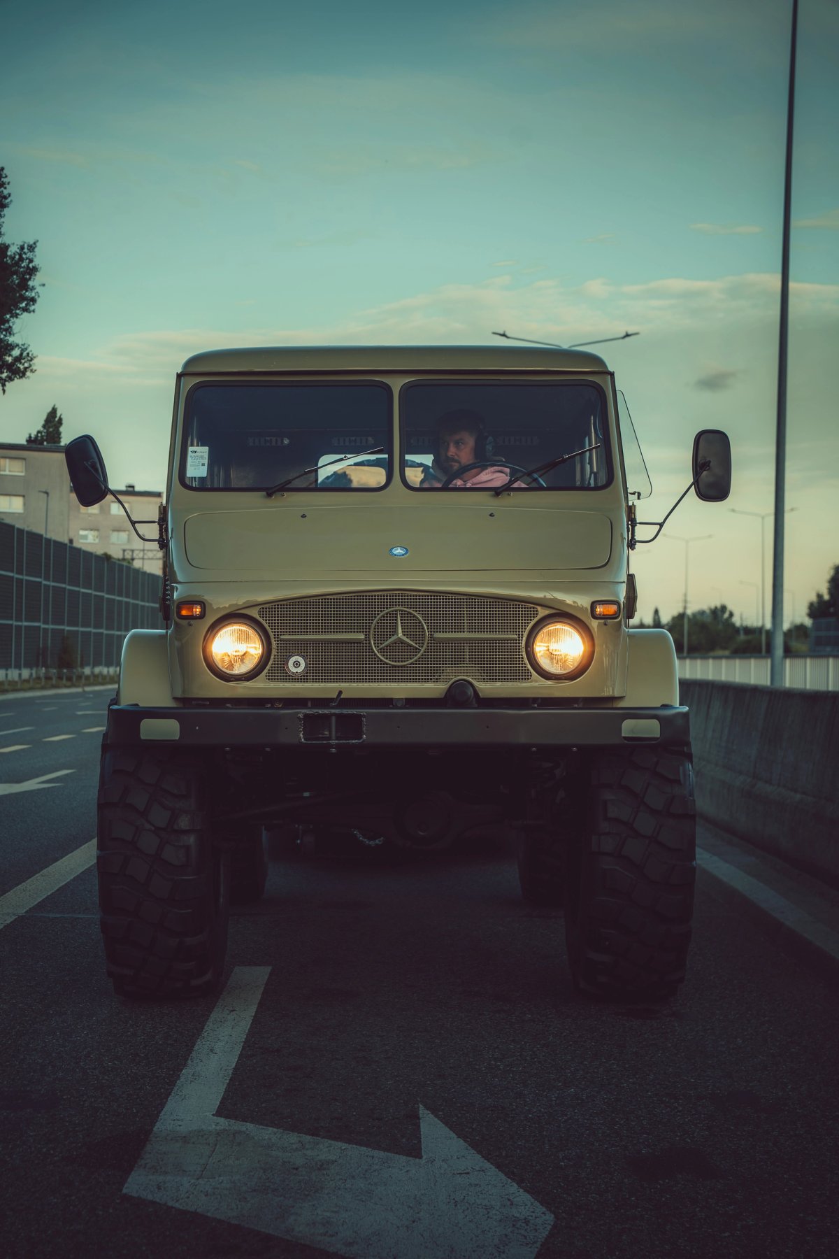 Unimog 404 front view head-on with headlights on and road arrow beneath