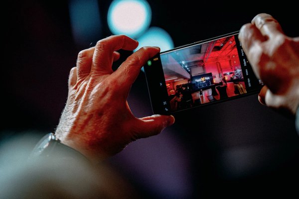 Hand holding a phone capturing the Red Fox Racing launch event with bokeh lights in the background