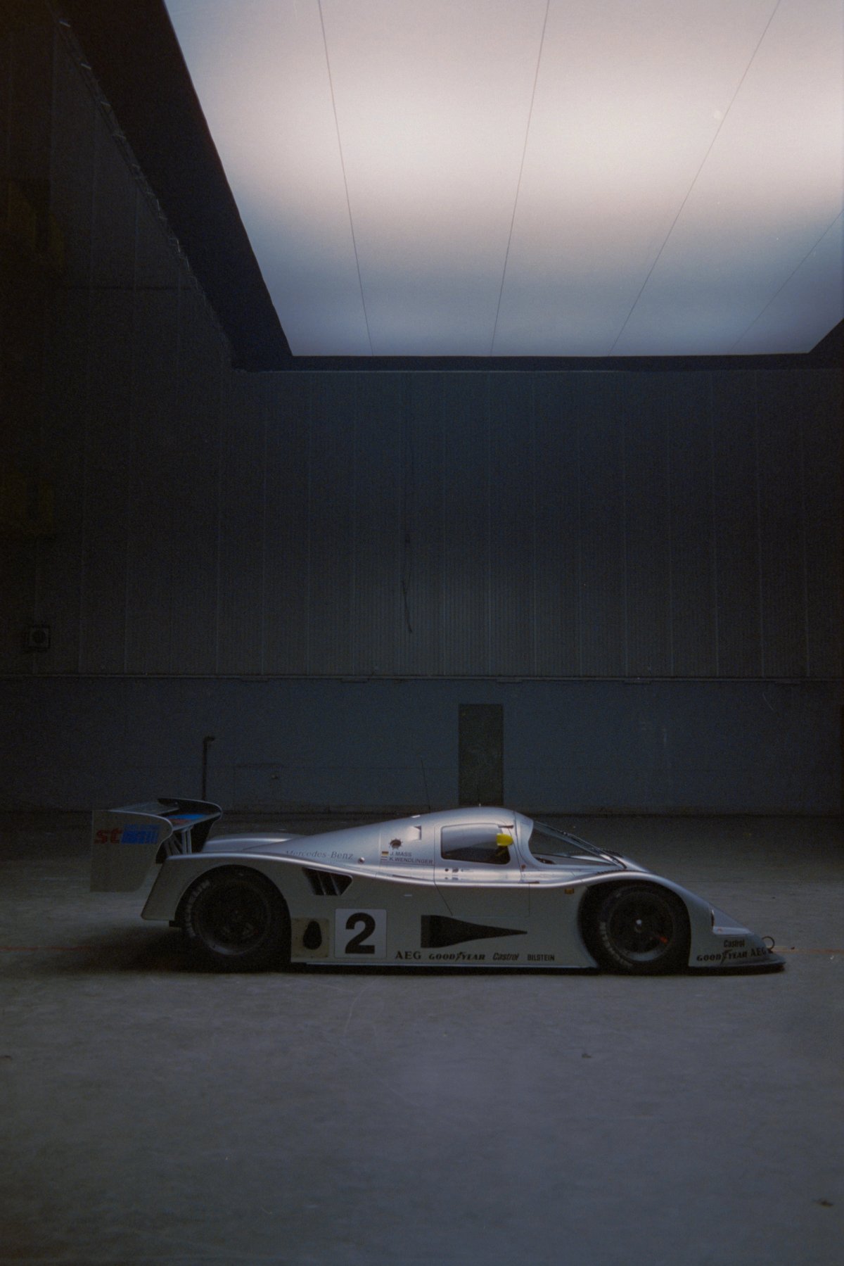 Mercedes Sauber C11 side profile against massive concrete wall with overhead light panel