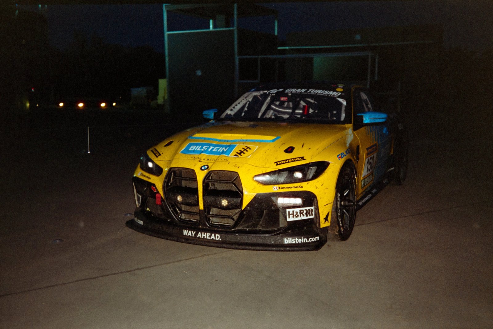 Yellow Bilstein BMW M4 GT3 alone on the esplanade after dark