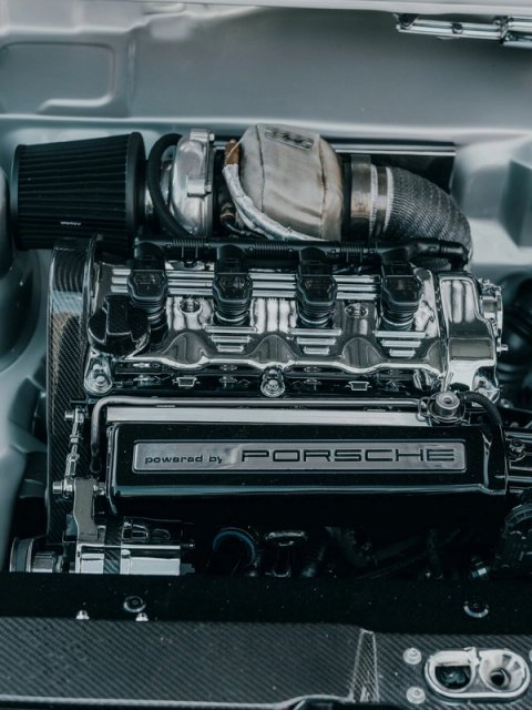 Turbocharged engine under a heat blanket, a powered by Porsche plaque on the cam cover