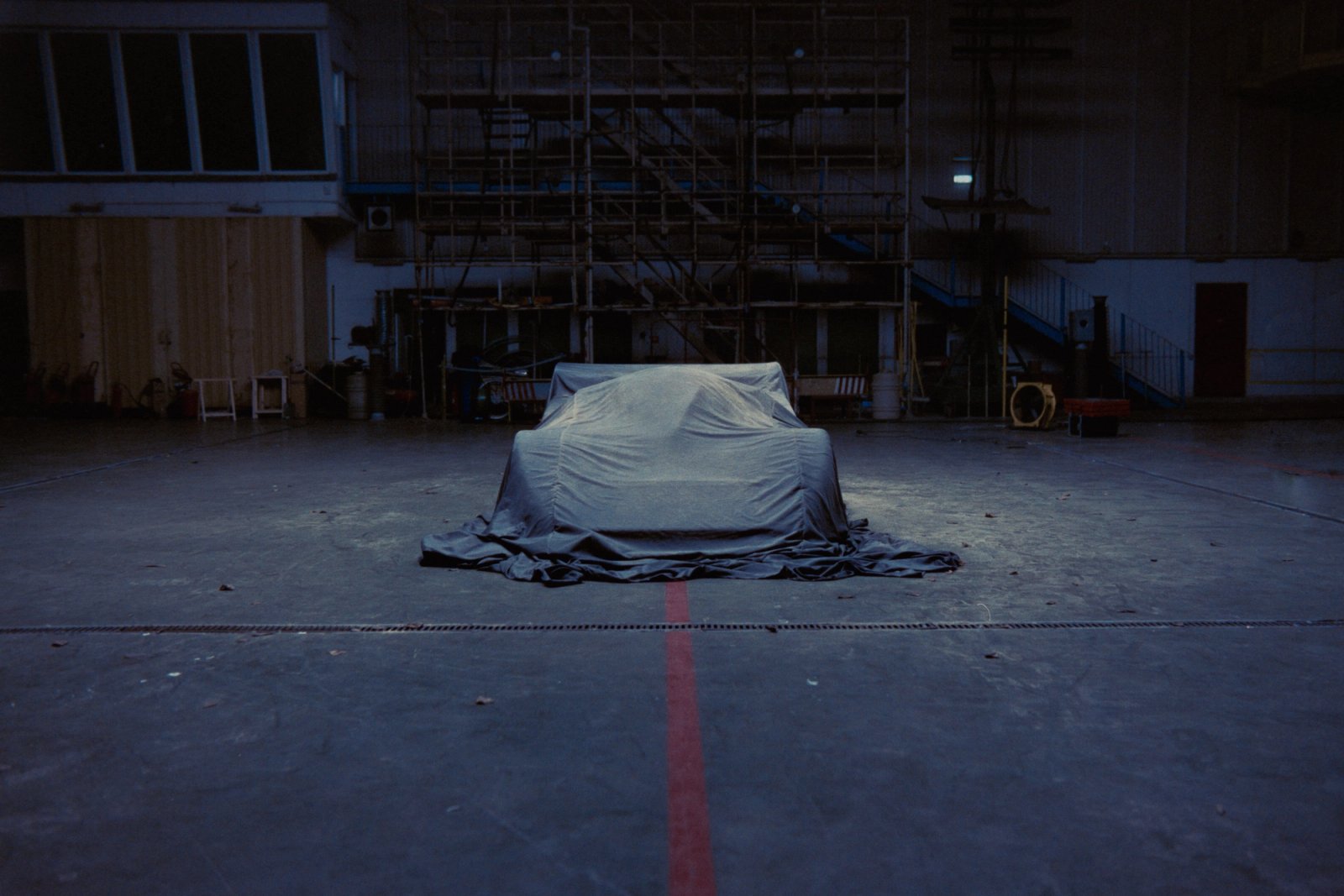 Mercedes Sauber C11 under a dust-covered sheet in the industrial hall with scaffolding behind