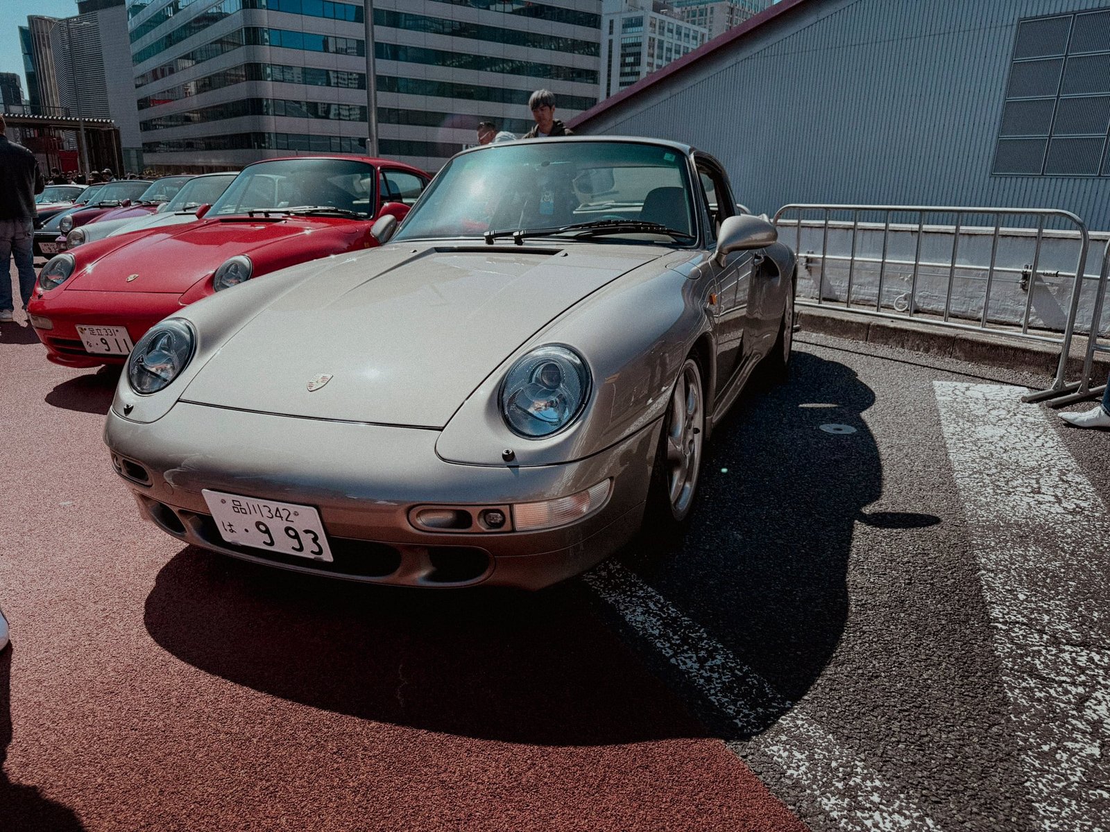 Silver Porsche 993 front three-quarter view with red 911 behind at Luftgekühlt Tokyo