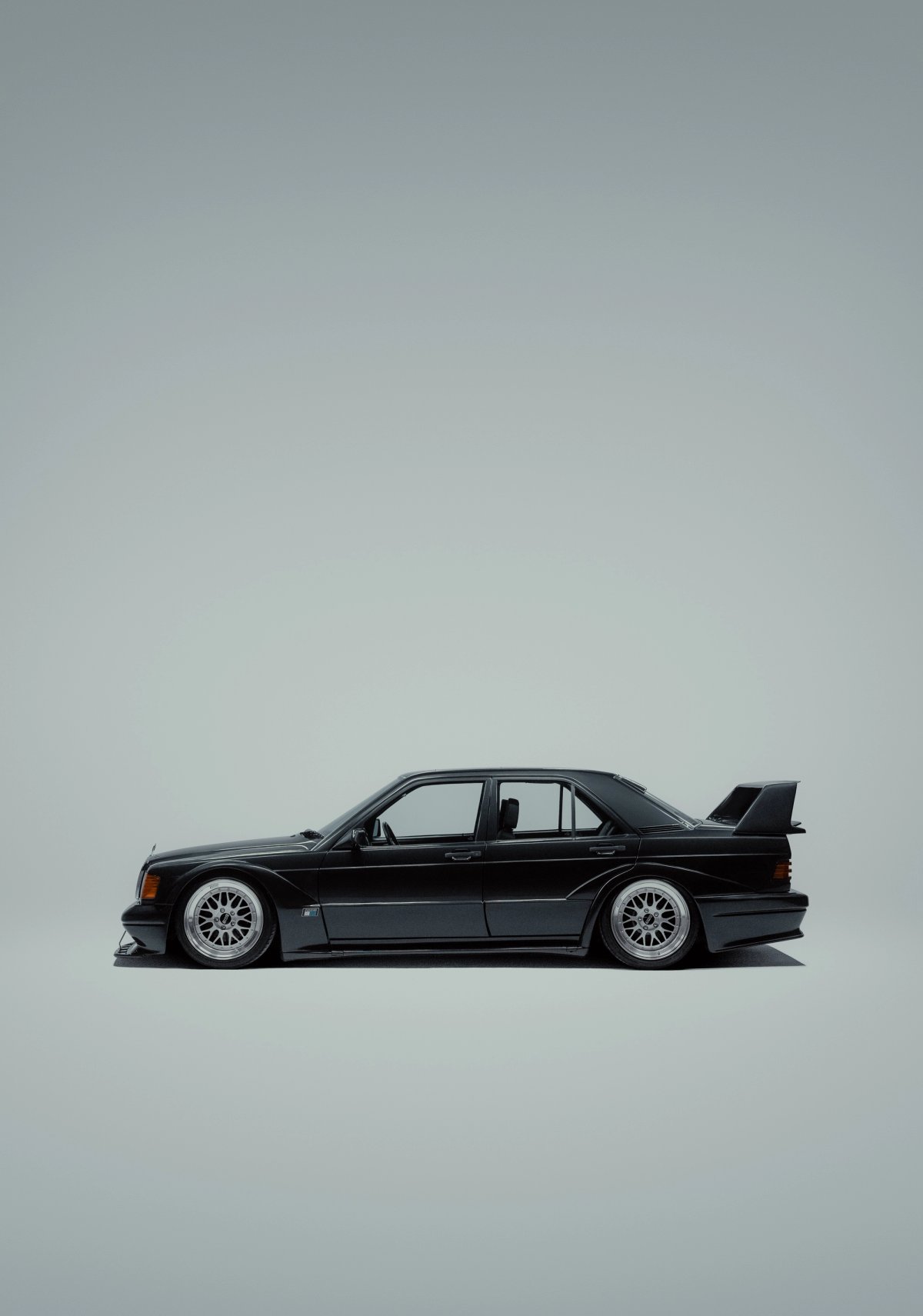 Mercedes 190E Evo II side profile on grey studio backdrop with massive negative space