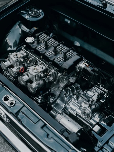 Engine bay with twin Weber carburettors on velocity stacks and a chromed gearbox