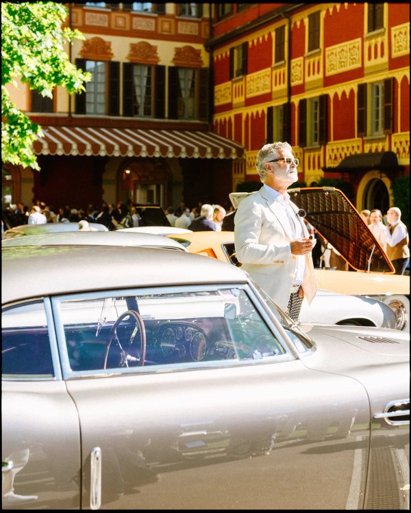 Italian villa facade with older man in white suit beside a silver classic car at Concorso d'Eleganza