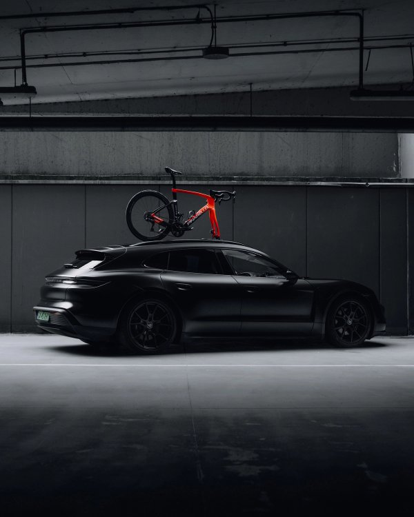 Black Porsche Taycan Cross Turismo with red Pinarello bike on roof rack in underground garage