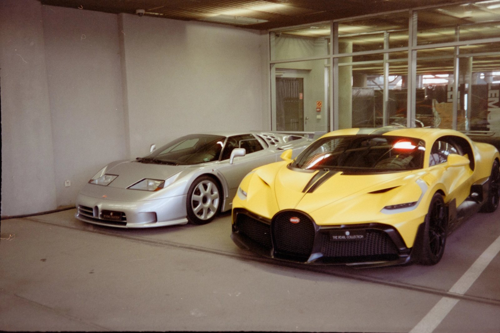 Silver Bugatti EB110 Super Sport next to yellow Bugatti Divo in a parking area