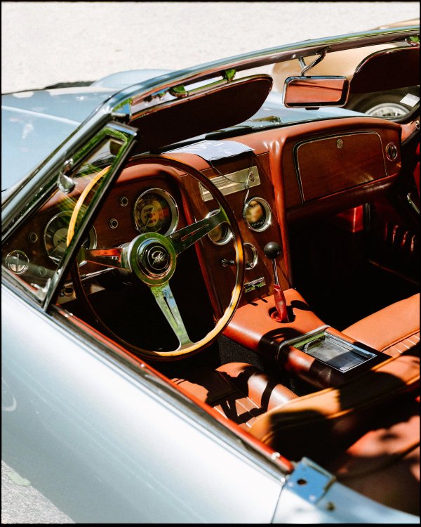 Vintage convertible interior with wooden steering wheel and burgundy leather seats