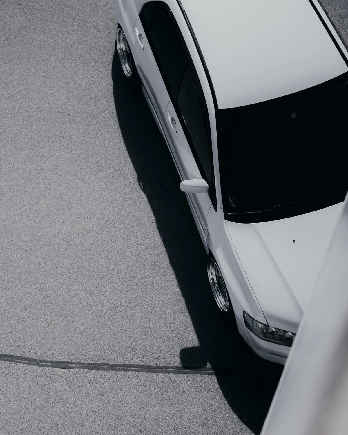 White Mitsubishi Lancer Evolution from above on vast grey asphalt