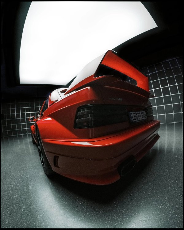 Rear three-quarter close-up of HWA EVO in red under a curved white softbox in a black-tiled room