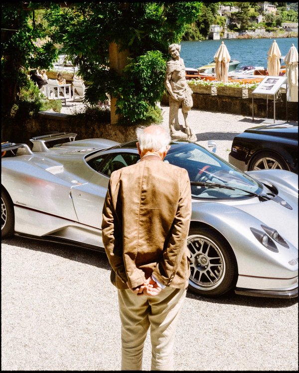 Pagani Zonda and dark supercar lineup with a figure walking toward Lake Como